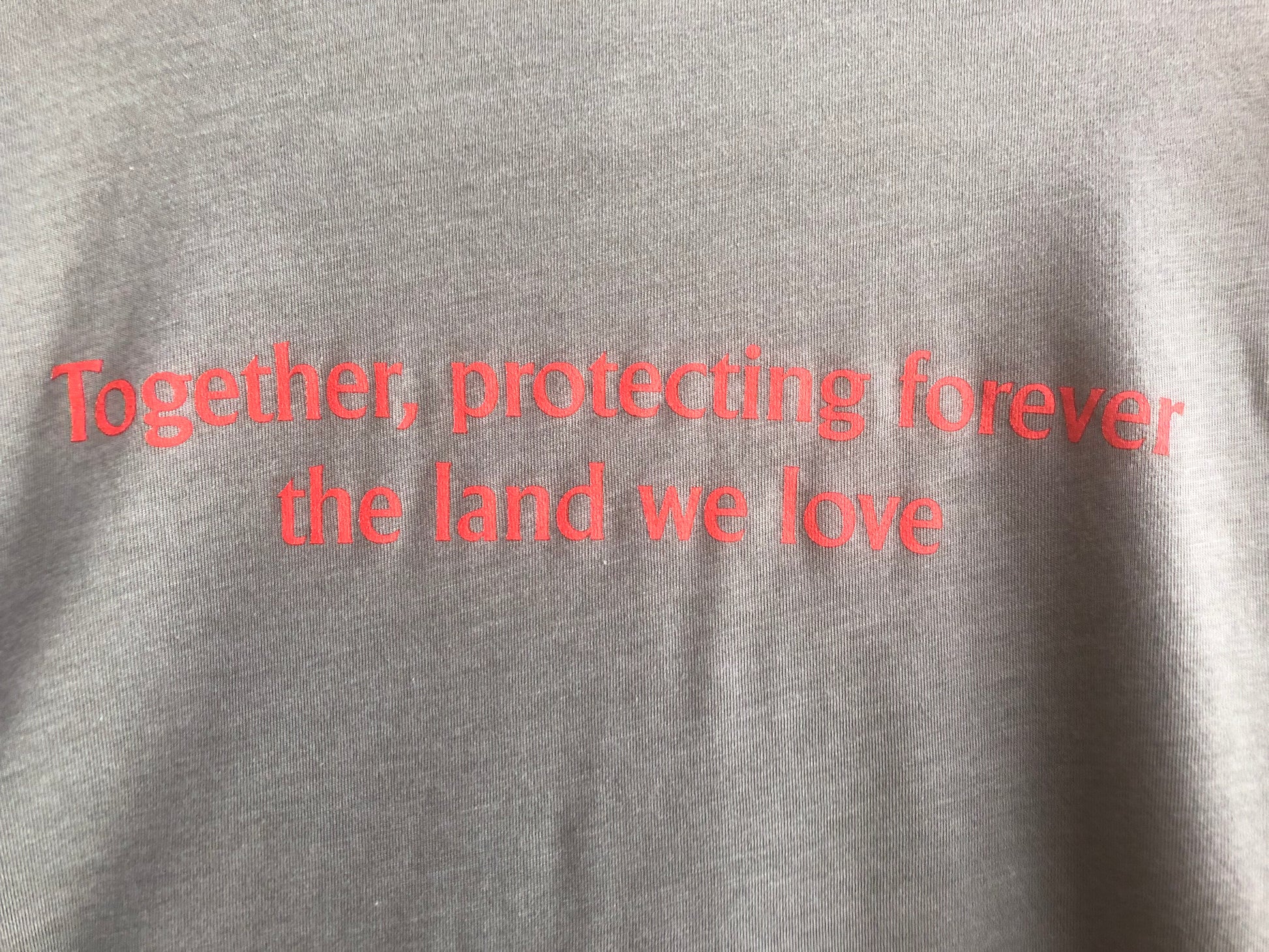 The back of the long sleeve gray shirt, with text that reads, "together, protecting forever the land we love."